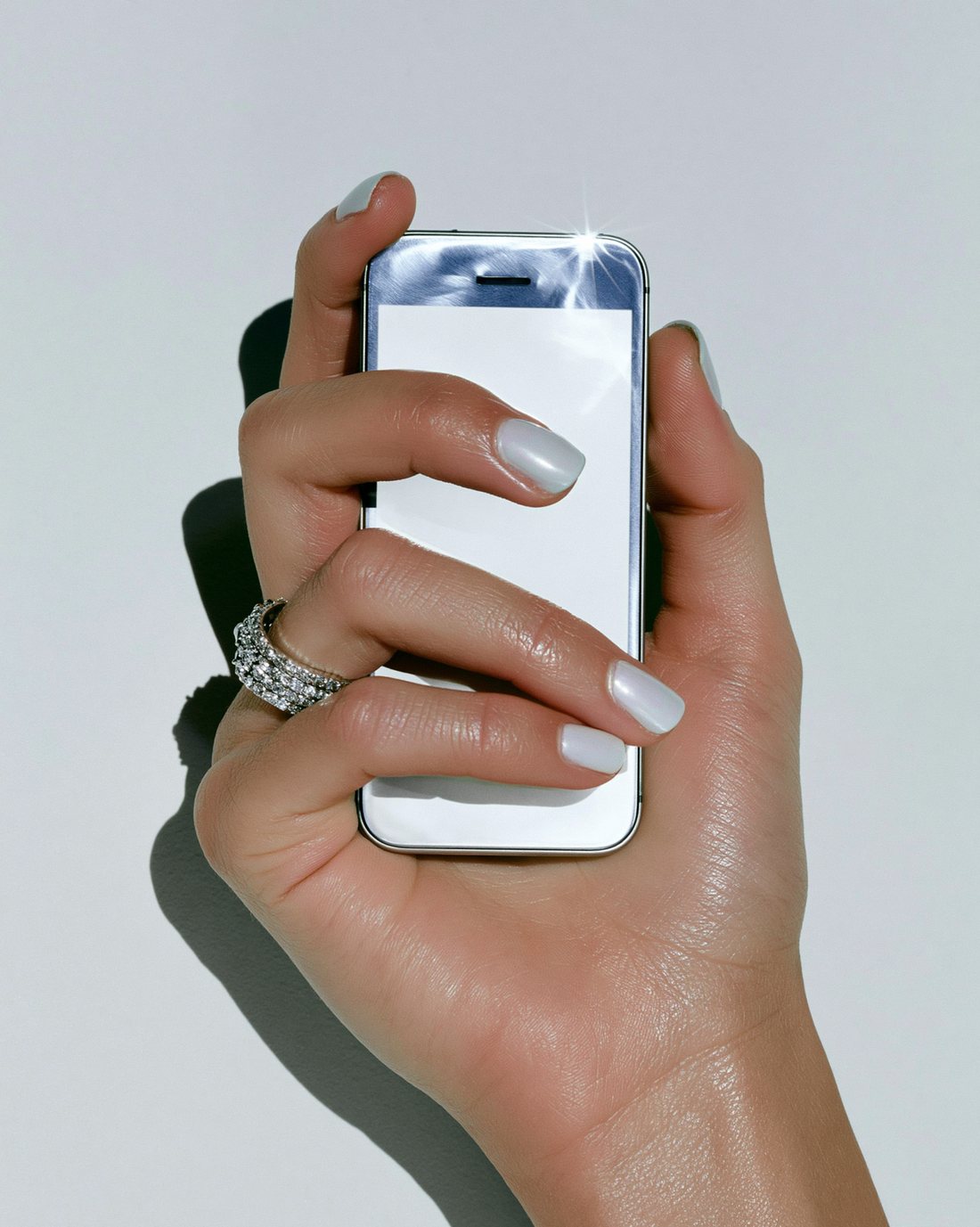 A manicured hand holding a phone with a bright nail-scan screen